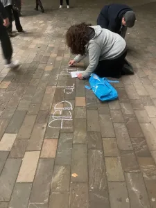 Amoorah schrijft een naam op de stoep.