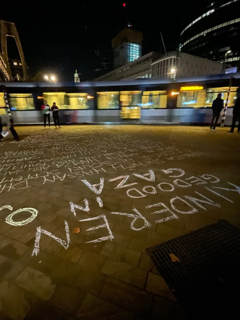 De Coolsingel. Een tram rijdt voorbij. Het torentje van het stadhuis is in de achtergrond te zien. In de voorgrond, gedraaid, de tekst: "kinderen gedood in Gaza"